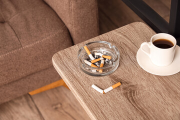 Ash tray with cigarettes and cup of coffee on table