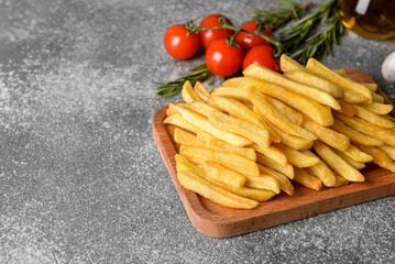 Wooden board with tasty french fries on grey background, closeup