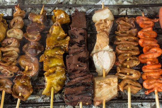 An assortment of various Filipino street foods on a charcoal grill.