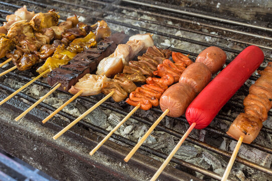 An assortment of various Filipino street foods on a charcoal grill.