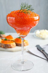 Cocktail glass of delicious red caviar with dill on light grey table