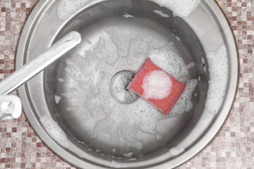 Silver sink with cleaning sponge and foam, closeup