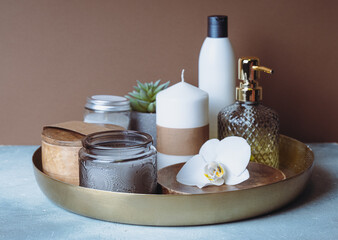 Spa still life with a natural cosmetics products, candles and flower on a copper plate.