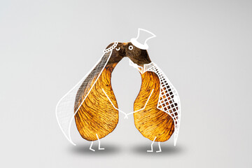 A couple kissing, represented by two maple seeds illustrated to make characters