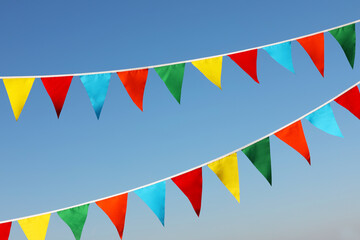 Obraz premium Buntings with colorful triangular flags against blue sky