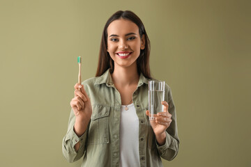 Young woman with bamboo tooth brush and glass of water on color background