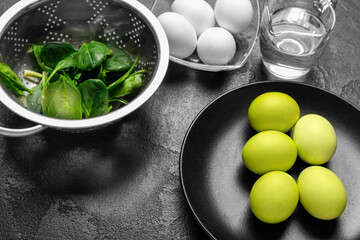Natural dyed Easter eggs and spinach leaves on dark table, closeup