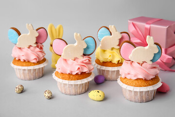 Tasty Easter cupcakes with eggs on grey background