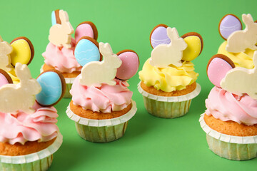 Tasty Easter cupcakes on green background, closeup