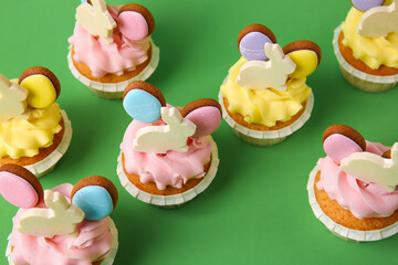 Tasty Easter cupcakes on green background