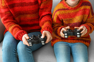 Little girl and her mother in warm sweaters playing video game at home, closeup © Pixel-Shot