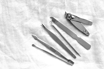 Manicure set tools on white fabric background.