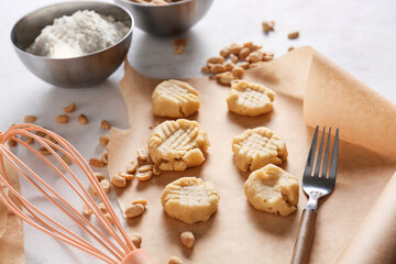 Parchment paper with uncooked peanut cookies on white background