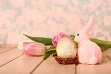 Beautiful Easter bunny, flowers and painted egg on pink wooden table