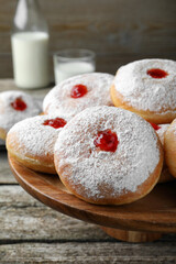Pastry stand with delicious jelly donuts on wooden table