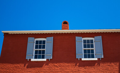 Solitary window on the exterior wall of the old house. Old red wall with two window with sashes.