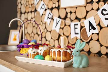 Tray with Easter cakes, eggs and rabbit on kitchen counter