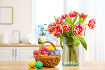 Basket of Easter eggs and vase with tulips on kitchen counter in light room