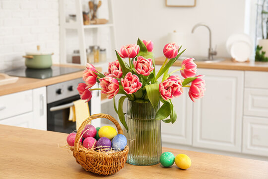 Basket of Easter eggs and vase with tulips on kitchen counter