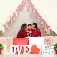 Latina mom, dad and daughter show their affection under a teepee with a sign that says "Love and family" celebrate Valentine's Day of Love and Friendship in February  © Arlette