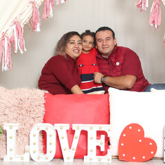 Latina mom, dad and daughter show their affection under a teepee with a sign that says 