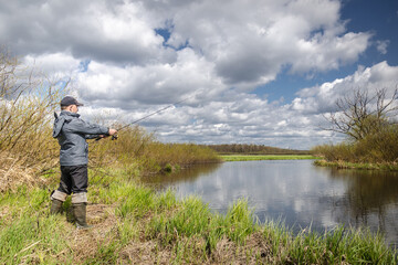 Fisherman in a jacket throws a spinning rod.