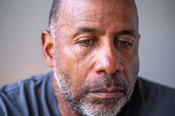 Portrait of a mature man looking sad with tears in his eyes.