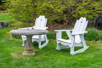 Antique moss-covered stone table and classic wooden chairs in the garden.