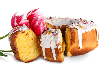 Pieces of tasty Easter cake and flowers on white background
