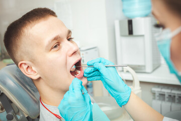 European female dentist doctor treats patient, examines mouth and teeth. Professional service, friendly, smiling, happy and satisfied, calm. mirror