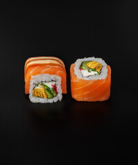 maki sushi with salmon on black background closeup