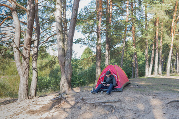 Fototapeta premium Man sitting in the forest near the tent.
