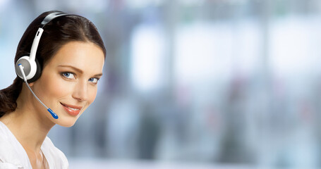 Fototapeta premium Call center help line service. Studio portrait of customer support phone sales operator in headset, blurred modern office background. Happy smiling business woman. Caller worker.