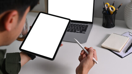 Asian male freelancer holding stylus pen and using digital tablet.
