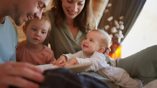 Happy young family with small children reading book in cabin on holiday.
