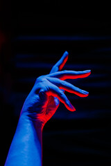 Close-up hand dance poses decorated with blue and red lights with blur black curtain in the...