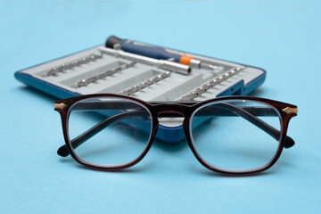 Glasses repair concept. Glasses for vision close-up and against the background of a screwdriver and...