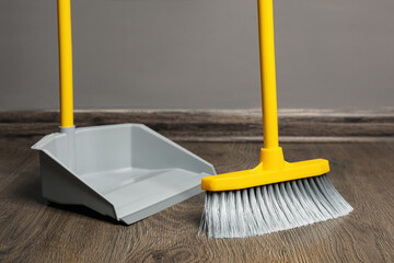 Sweeping wooden floor with plastic broom and dustpan indoors