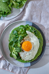 Delicious spinach crepes green colored pancake with vegetables on a table