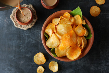 spicy masala tapioca chips Keripik singkong or Cassava chips Indian milk tea chai India Indonesia Brazil Sri Lanka Kerala fried snacks  food banana leaf background. tea time food fried in coconut oil