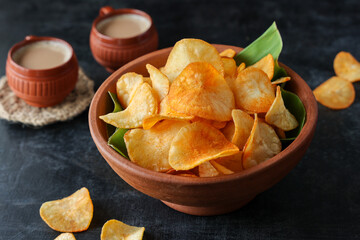 spicy masala tapioca chips Keripik singkong or Cassava chips Indian milk tea chai India Indonesia Brazil Sri Lanka Kerala fried snacks  food banana leaf background. tea time food fried in coconut oil