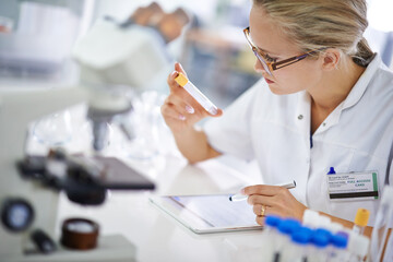 Research and development. A young scientist recording her findings on a tablet.