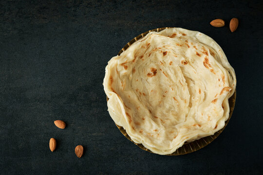Kerala paratha porotta meat beef curry roti Malabar parotta barotta is Indian layered flatbread for breakfast snack, popular street food India ramadan festival . Maida wheat flour Cooking the dough.