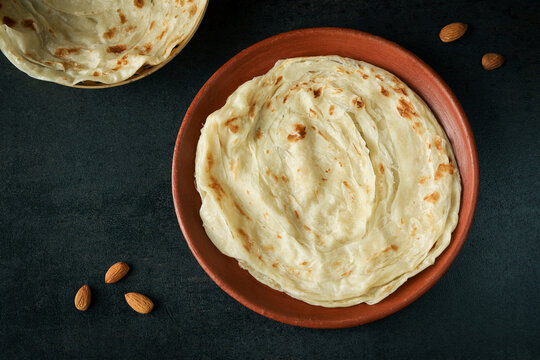 Kerala paratha porotta meat beef curry roti Malabar parotta barotta is Indian layered flatbread for breakfast snack, popular street food India ramadan festival . Maida wheat flour Cooking the dough.