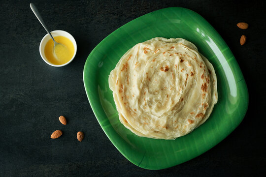 Kerala paratha porotta ghee meat curry roti Malabar parotta barotta is Indian layered flatbread for breakfast snack, popular street food India ramadan festival . Maida wheat flour Cooking the dough.