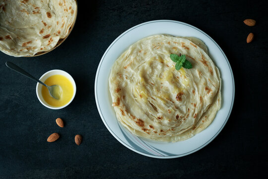 Kerala paratha porotta ghee meat curry roti Malabar parotta barotta is Indian layered flatbread for breakfast snack, popular street food India ramadan festival . Maida wheat flour Cooking the dough.