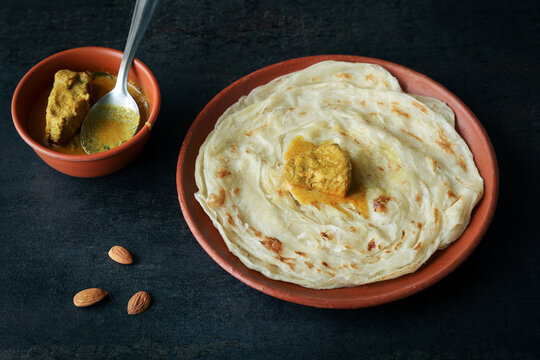 Kerala paratha porotta meat chicken curry roti Malabar parotta barotta Indian layered flatbread for breakfast snack, popular street food India ramadan festival . Maida wheat flour Cooking the dough.