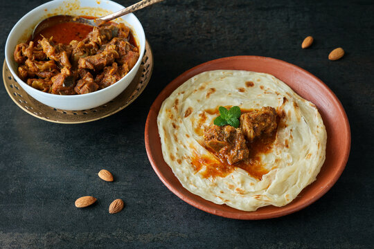 Kerala paratha porotta meat beef curry roti Malabar parotta barotta is Indian layered flatbread for breakfast snack, popular street food India ramadan festival . Maida wheat flour Cooking the dough.
