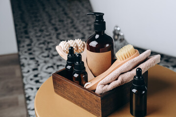 Shampoo shower gel,  Lotion, cream, massage brushes and anti-cellulite in a basket on the table near the bathtub in the bathroom. Body and face care beauty bath set. 