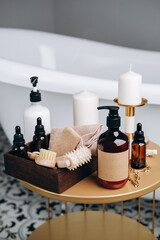 Shampoo shower gel,  Lotion, cream, massage brushes and anti-cellulite in a basket on the table near the bathtub in the bathroom. Body and face care beauty bath set. 